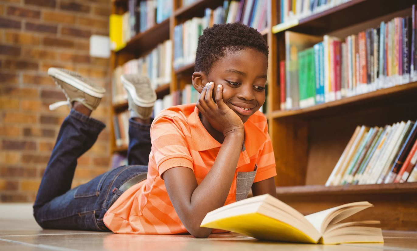 A young boy reading a book in a library