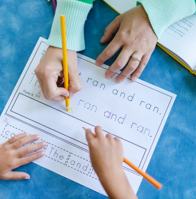A child practices handwriting with an adult