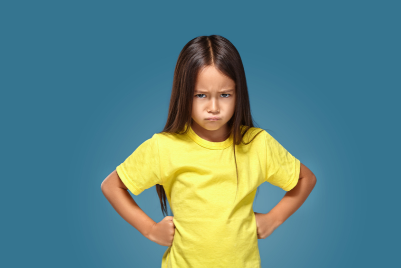 a young girl in a yellow t-shirt pouts