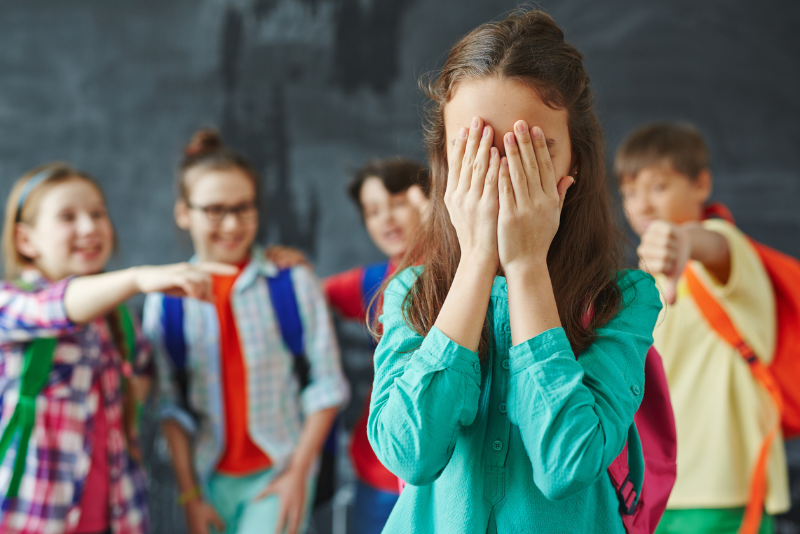 A child cries while a group of students bullies her.