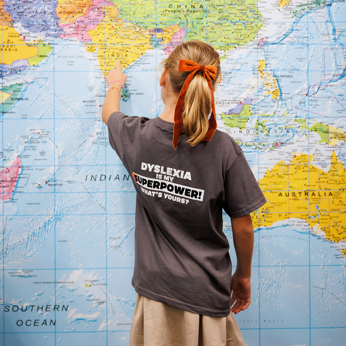 A girl pointing to a large world map.