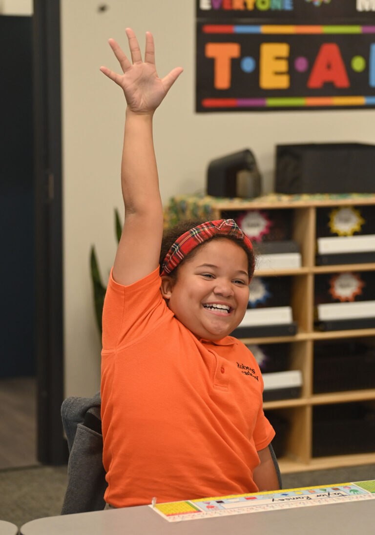 Child raising their hand in a classroom