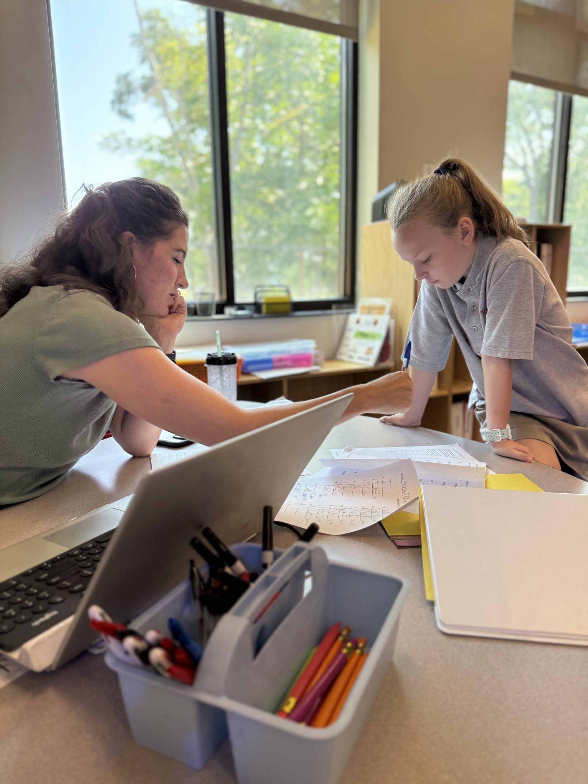 A Roberts Academy student works with a reading instructor in a well-lit classroom