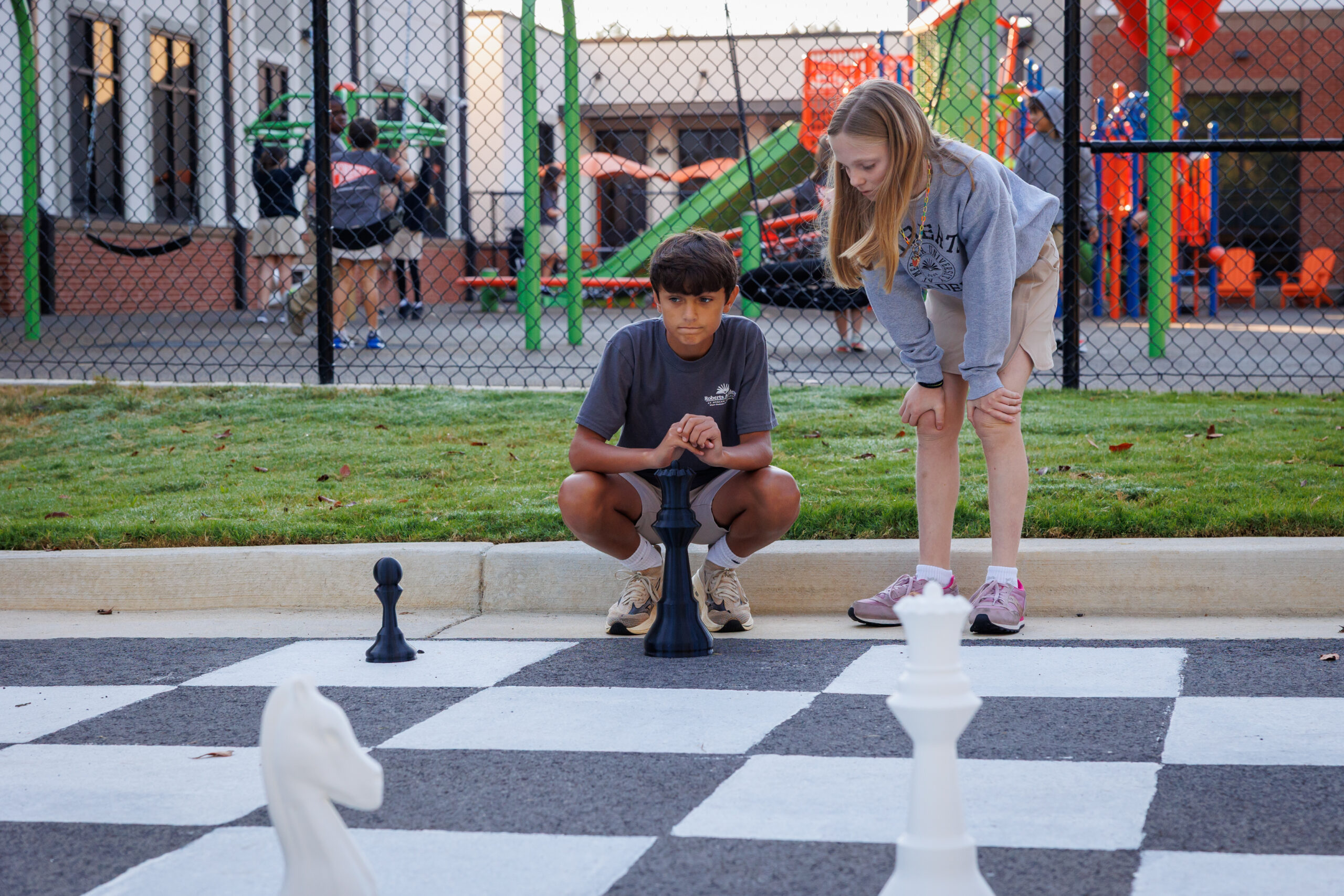 Roberts Academy students playing outdoor chess with mentorship from Mercer University Chess Team, building confidence and problem-solving skills through the game.