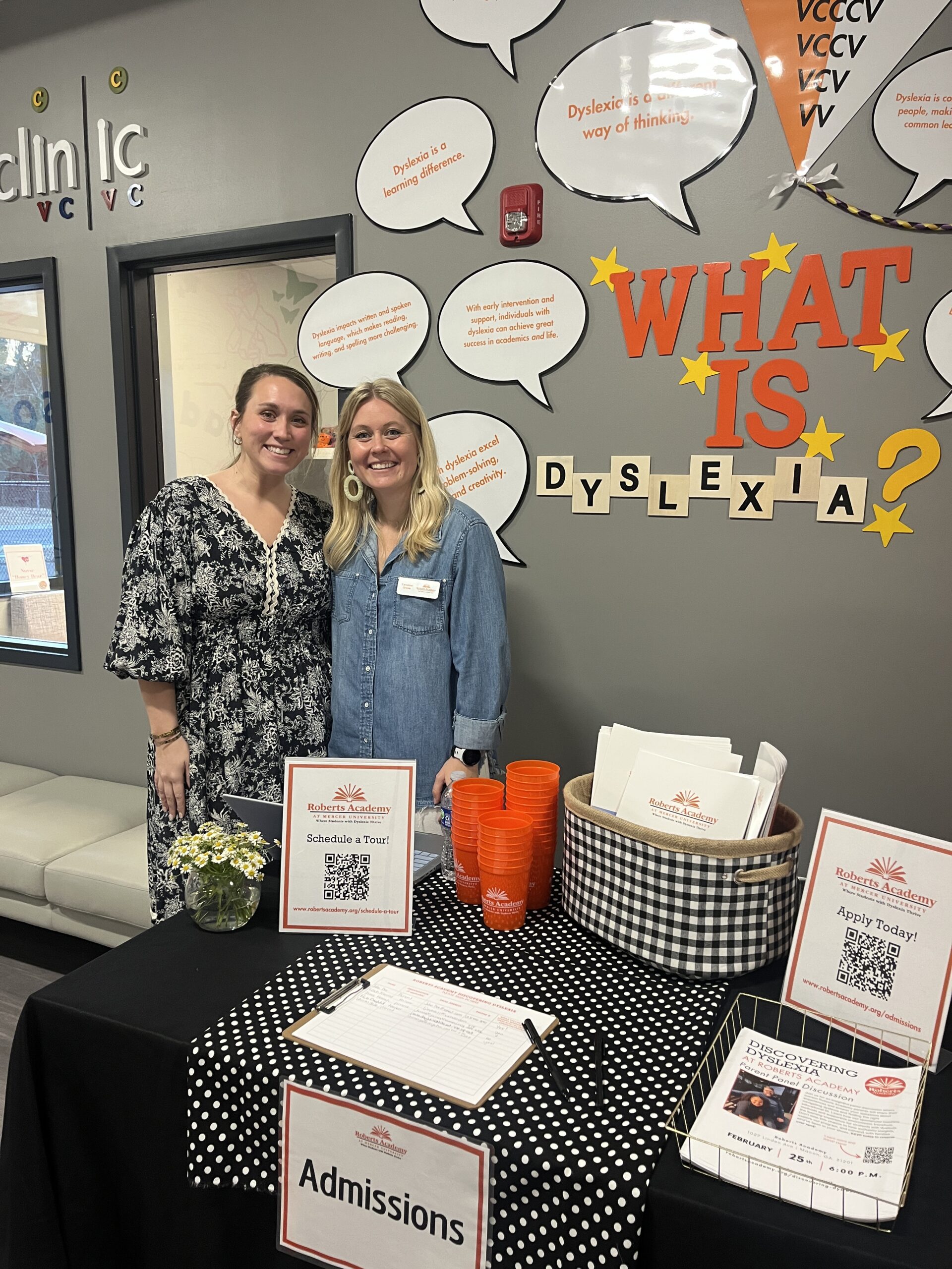 Roberts Academy at Mercer University teachers Elizabeth Eidson and Caroline Grove stand in front of signage that reads "What is Dyslexia?"